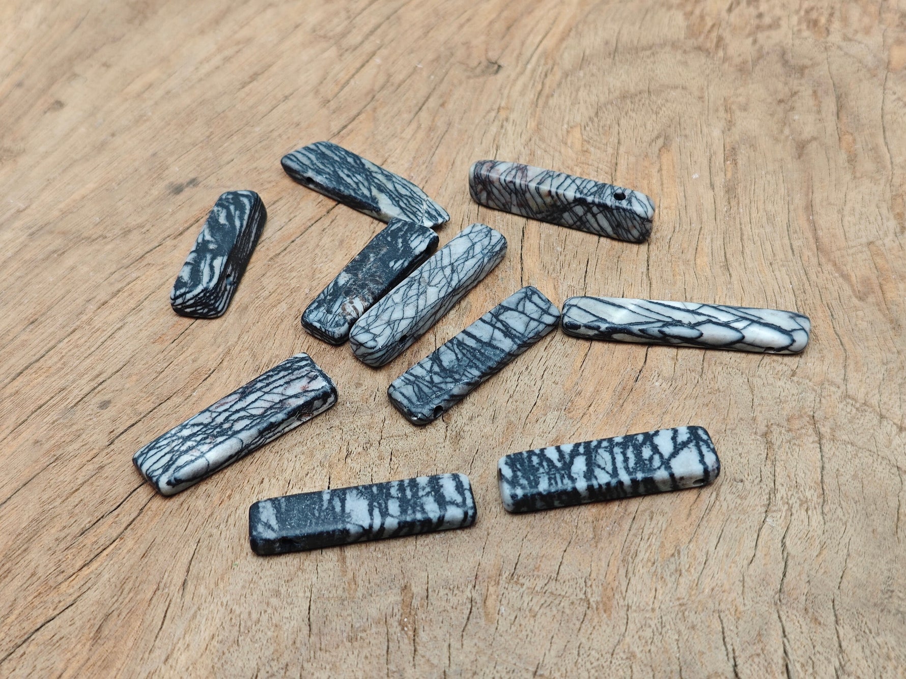 Black network jasper gemstone pendant from GemstoneGO featuring a drilled tumbled stone with natural patterns on a silver chain.
