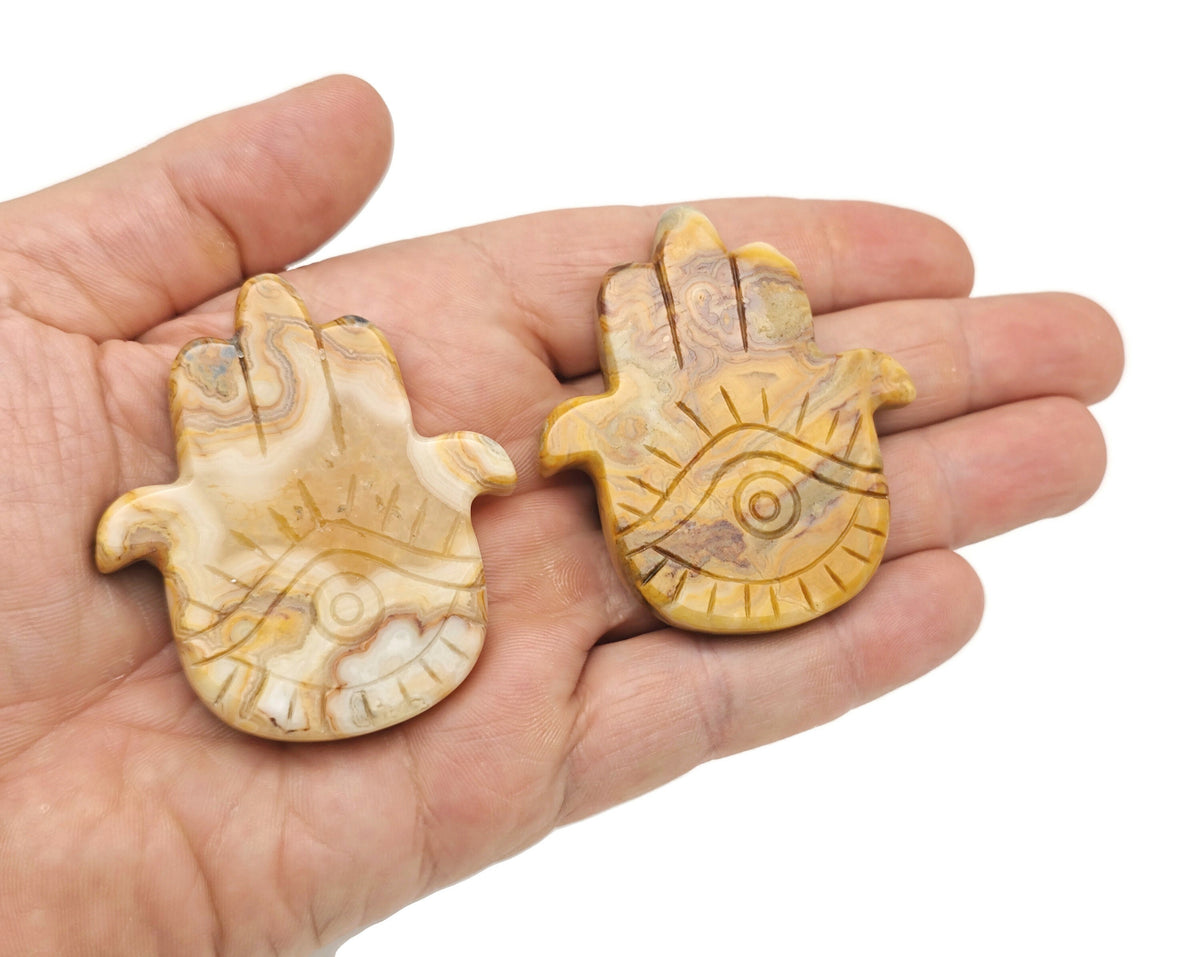 Evil Eye hand gemstone carving pocket crystal with chakra and meditation symbols, used for spiritual healing and protection.