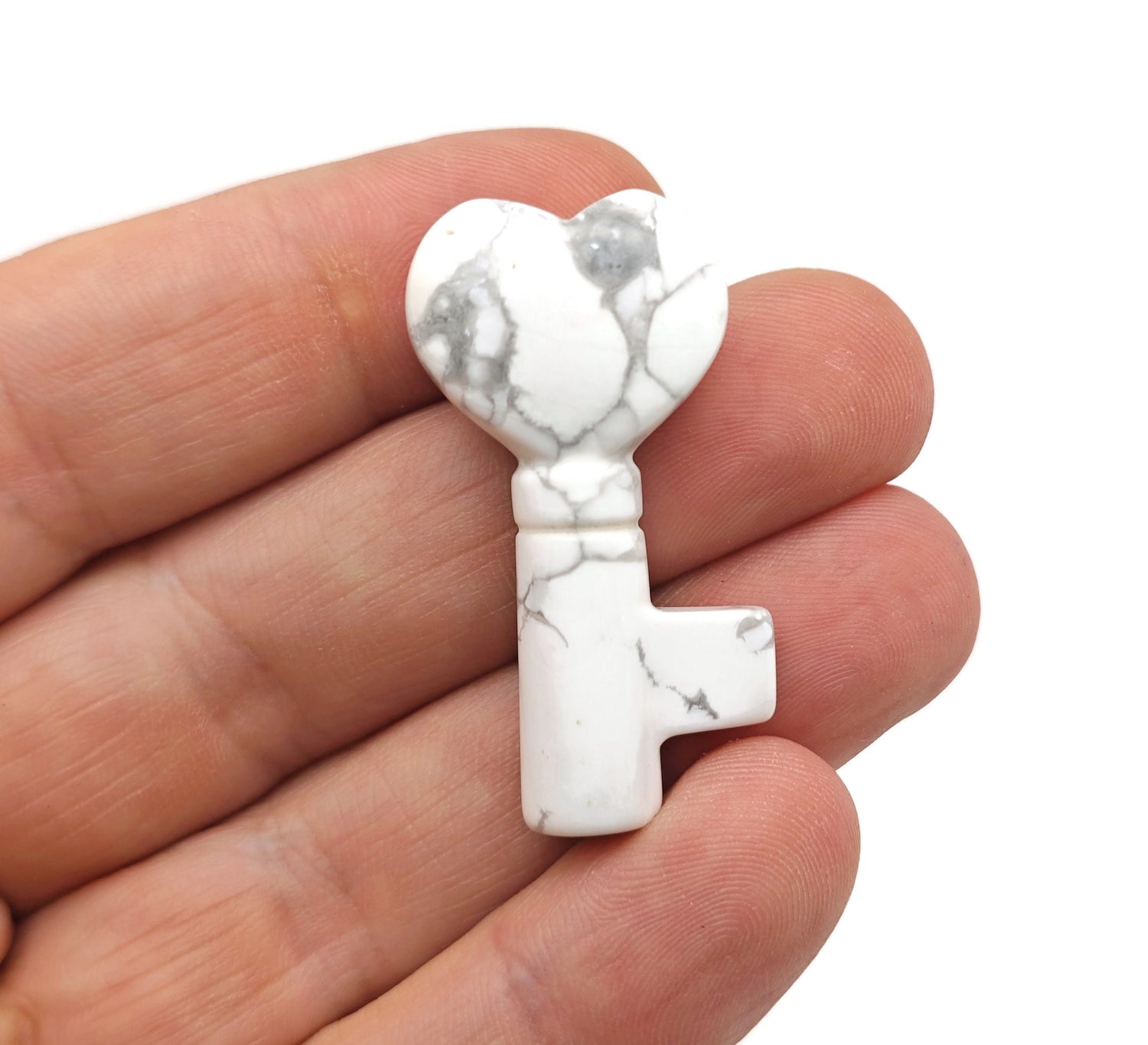 Howlite key gemstone carving, 40mm, from GemstoneGO, showcasing a smooth, polished white stone with gray veining on a neutral background.