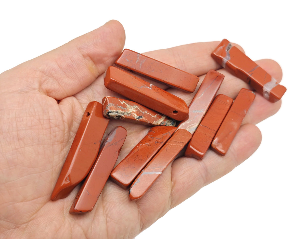 Red Jasper drilled tumbled gemstone pendant from GemstoneGO, showcasing a smooth, polished red jasper stone with a drilled hole for jewelry.