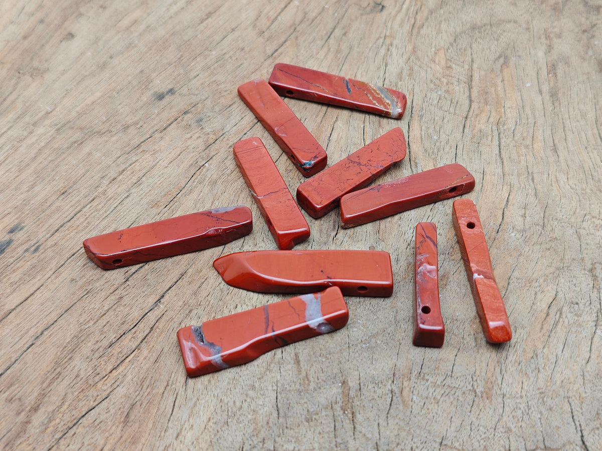 Red Jasper drilled tumbled gemstone pendant from GemstoneGO, showcasing a smooth, polished red jasper stone with a drilled hole for jewelry.