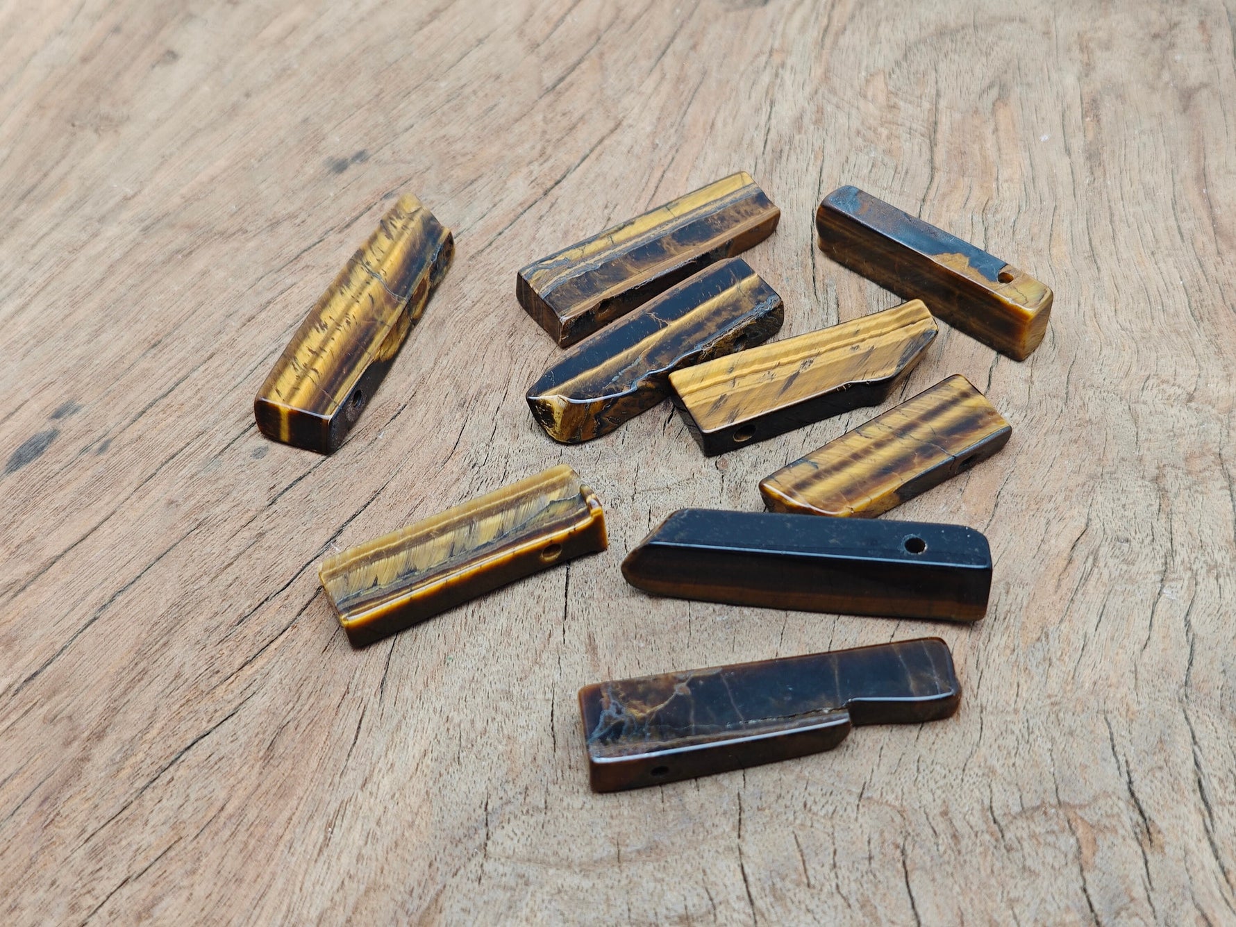 Tiger Eye drilled tumbled gemstone pendant from GemstoneGO, showcasing a smooth, polished oval with natural golden-brown hues.