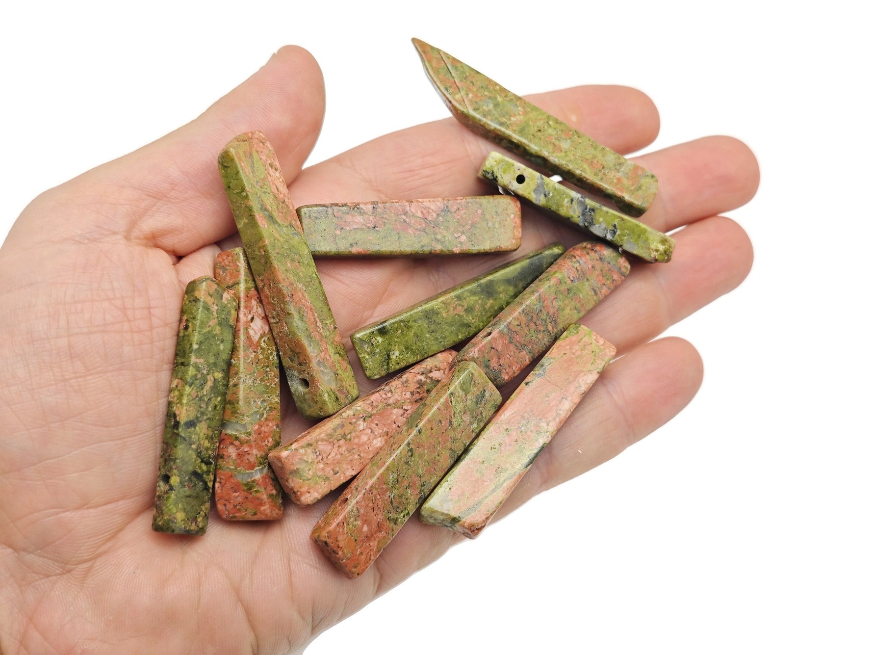 Unakite drilled tumbled gemstone pendant showing smooth, polished pink and green stone with a hole for jewelry attachment.