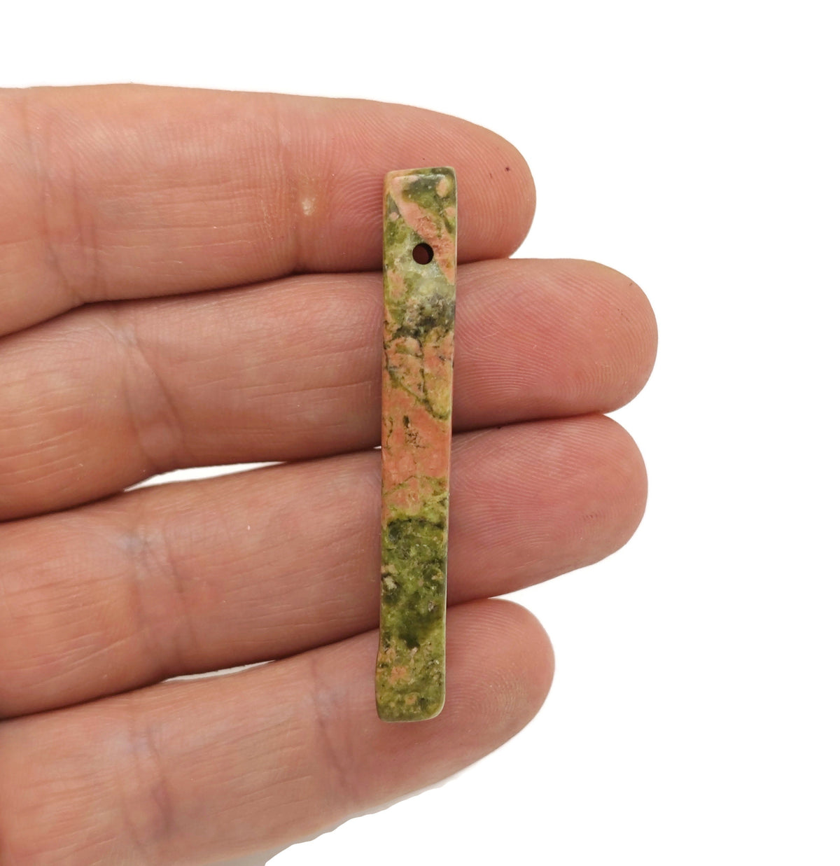 Unakite drilled tumbled gemstone pendant from GemstoneGO showing a smooth, polished pink and green mineral pendant on a neutral background.