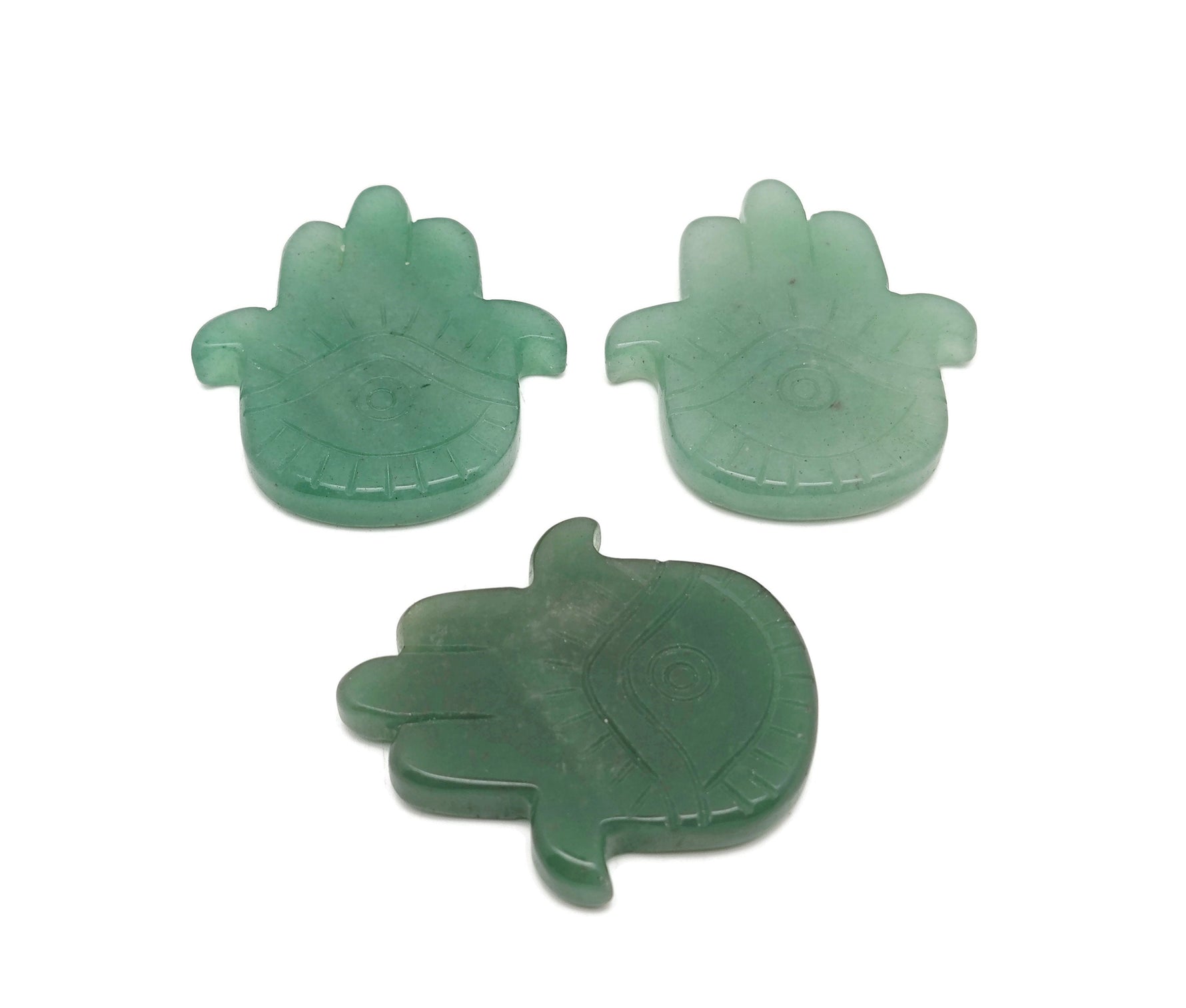Aventurine evil eye gemstone carving held in hand, featuring intricate hand-carved evil eye design by GemstoneGO.