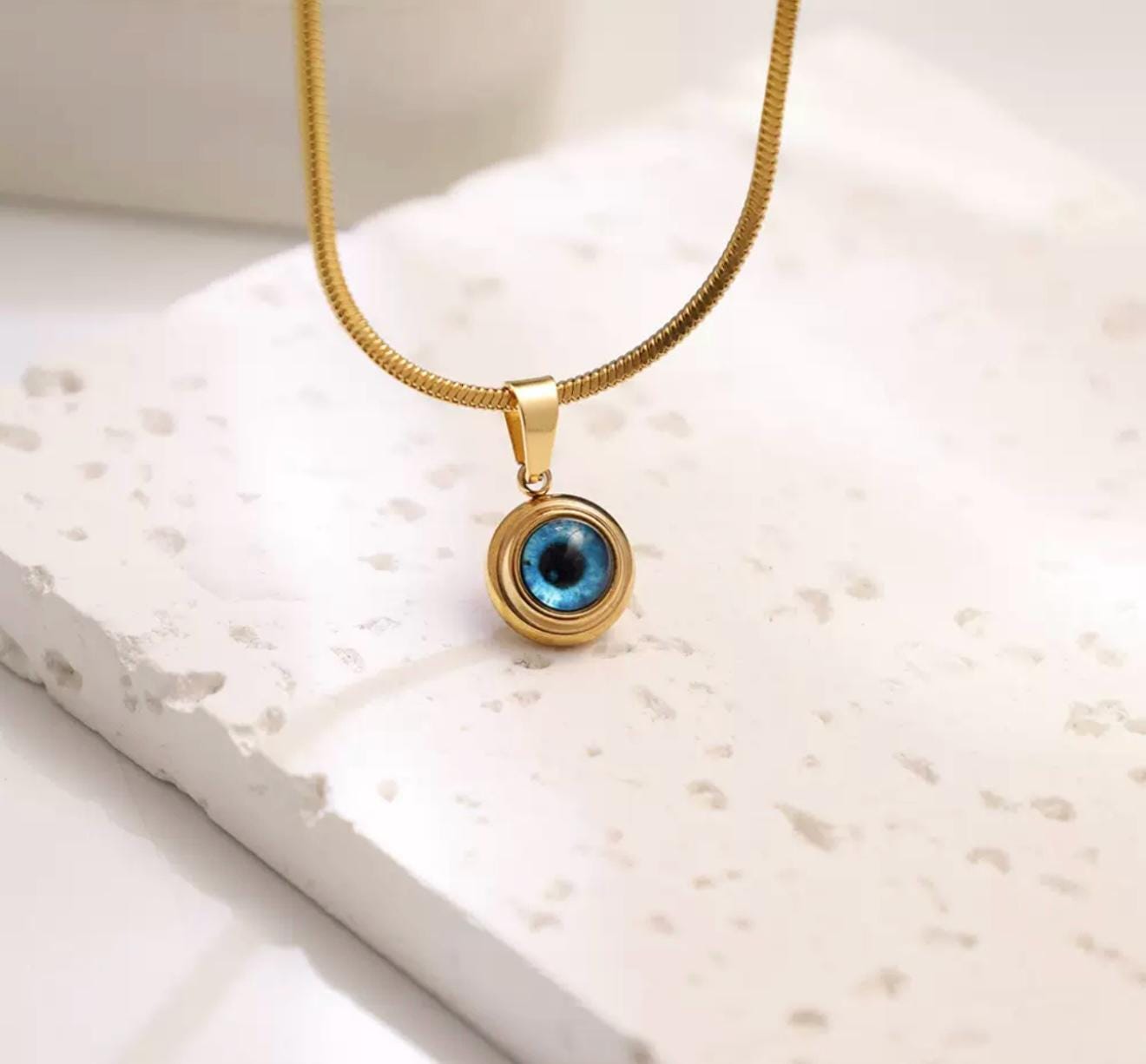 Gold evil eye pendant from GemstoneGO featuring a silver Nazar design, small and stylish jewelry accessory.