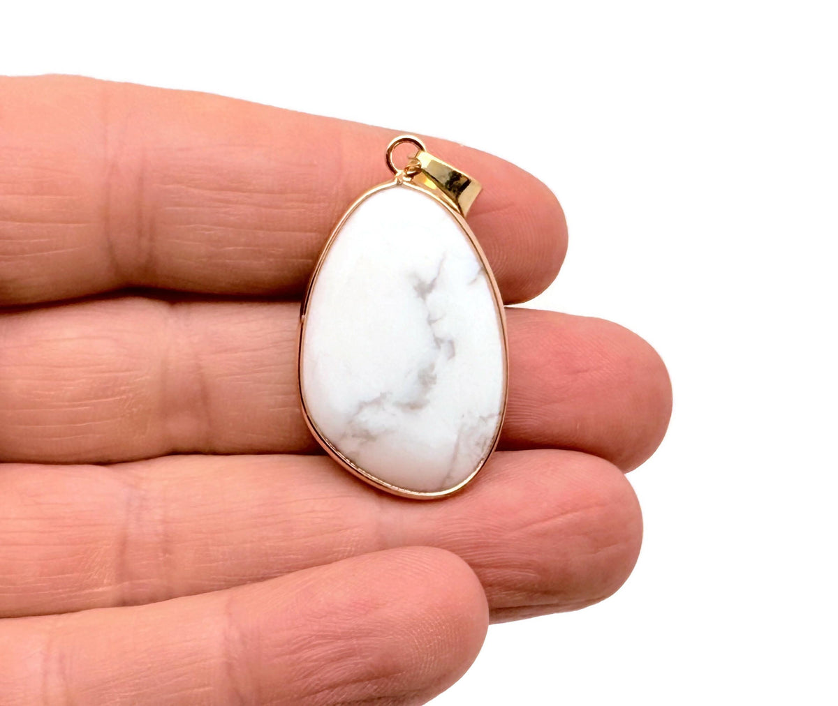 Dainty Howlite gold gemstone pendant from GemstoneGO with a polished white stone and gold-tone bail, suitable for jewelry DIY charms.