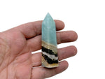 Caribbean Calcite obelisk tower crystal from GemstoneGO, showing a polished mineral with natural orange and white hues.