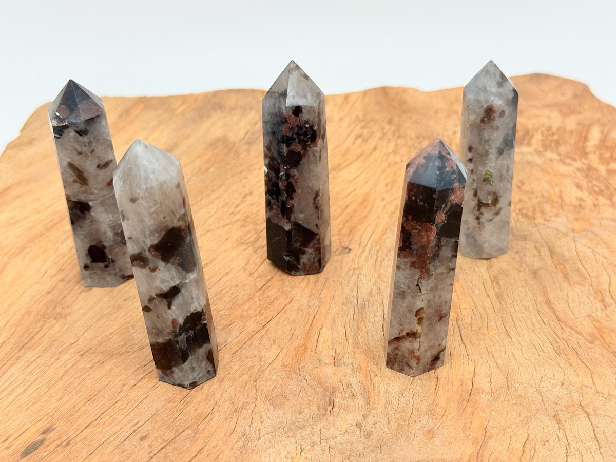 Garnet and black tourmaline obelisk tower crystal from GemstoneGO showing polished gemstone with striations and pointed top.