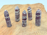 Red zebra calcite obelisk tower crystal from GemstoneGO, featuring vibrant red and white striped patterns and a pointed tip.