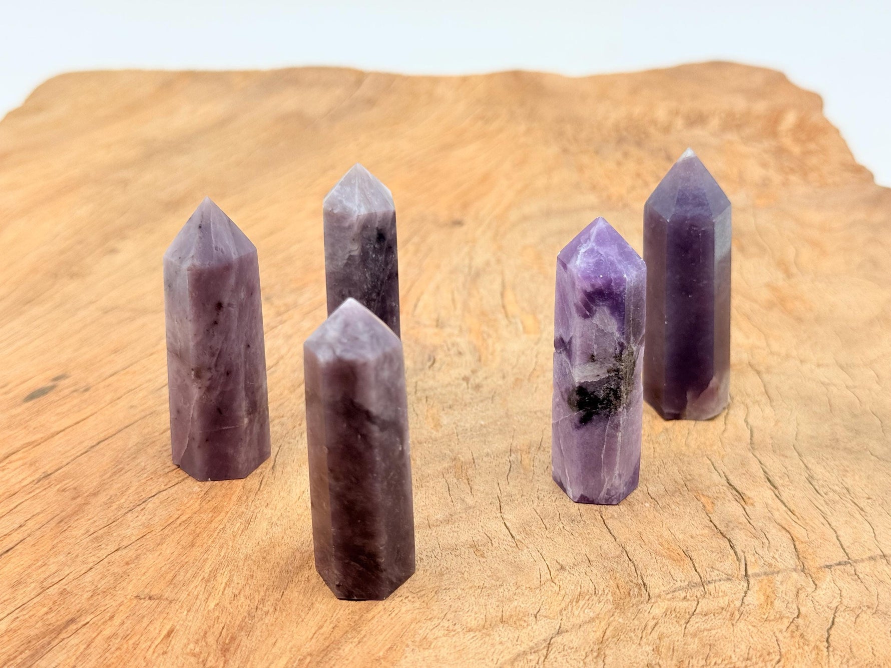 Lepidolite obelisk crystal tower from GemstoneGO, showcasing a purple and silver-toned mineral with natural striations.