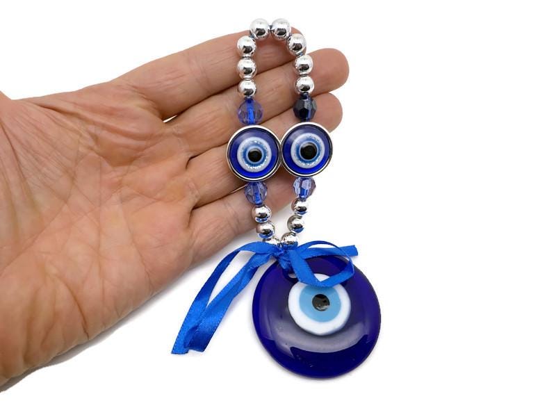 Blue glass evil eye charm with intricate design, Turkish Nazar charm used for protection and home decor, by GemstoneGO.