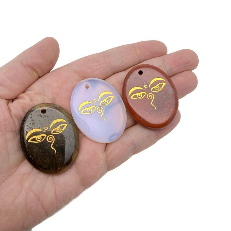 Crystal Buddha Eyes engraved amulet by GemstoneGO featuring spiritual symbols and drilled gemstone for insight and guidance.