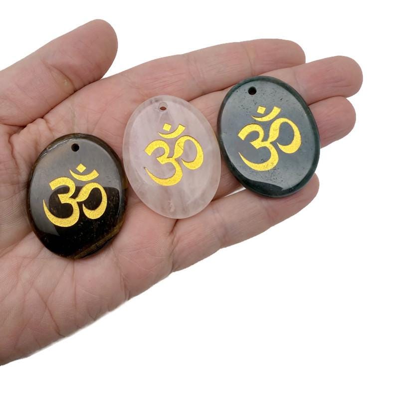 Crystal pendant with engraved Om symbol, drilled for jewelry, representing spiritual insight and guidance in a clear, polished design.