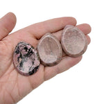 Rhodonite worry stone from GemstoneGO, 45mm soothing crystal with polished smooth surface and vibrant pink and black marbling.