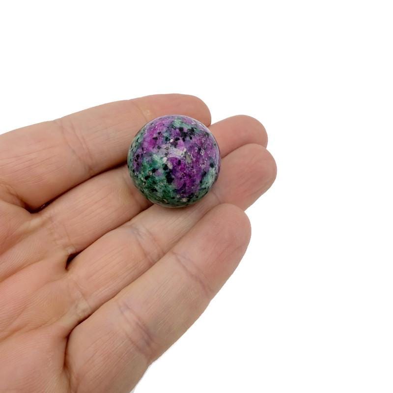 25mm natural crystal sphere from GemstoneGO, showcasing a clear, smooth glass-like gemstone ball on a neutral background.