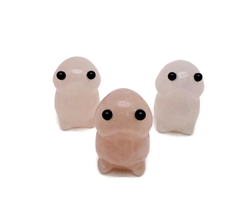 Handcrafted rose quartz frog monster crystal carving from GemstoneGO, detailed gemstone creature statue on a smooth surface.
