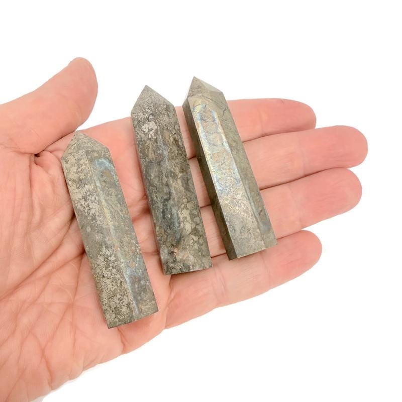 Pyrite obelisk tower crystal from GemstoneGO, featuring a shiny metallic gold finish and natural stone texture.