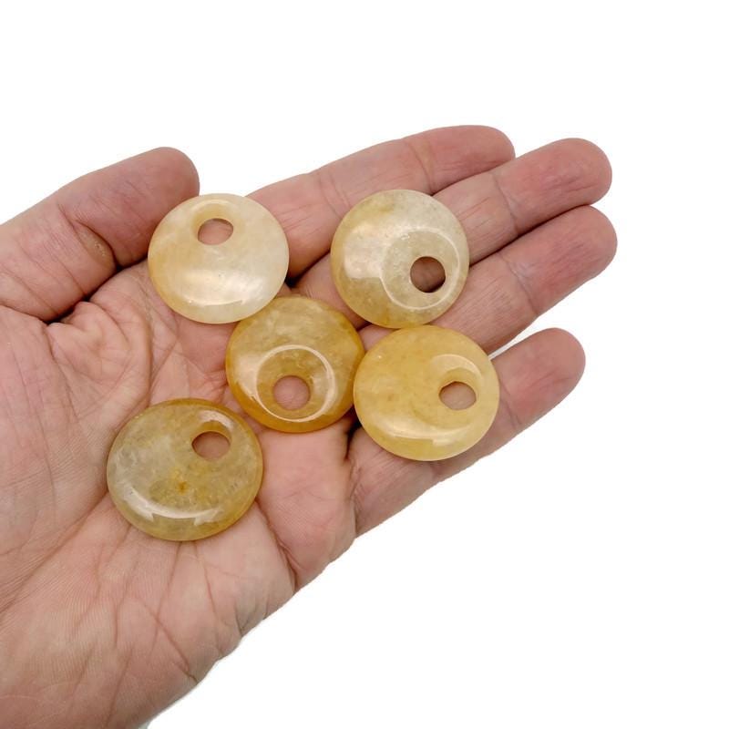 Yellow jade crystal donut pendant from GemstoneGO, 30mm Pi stone with a smooth, polished surface and vibrant yellow color.