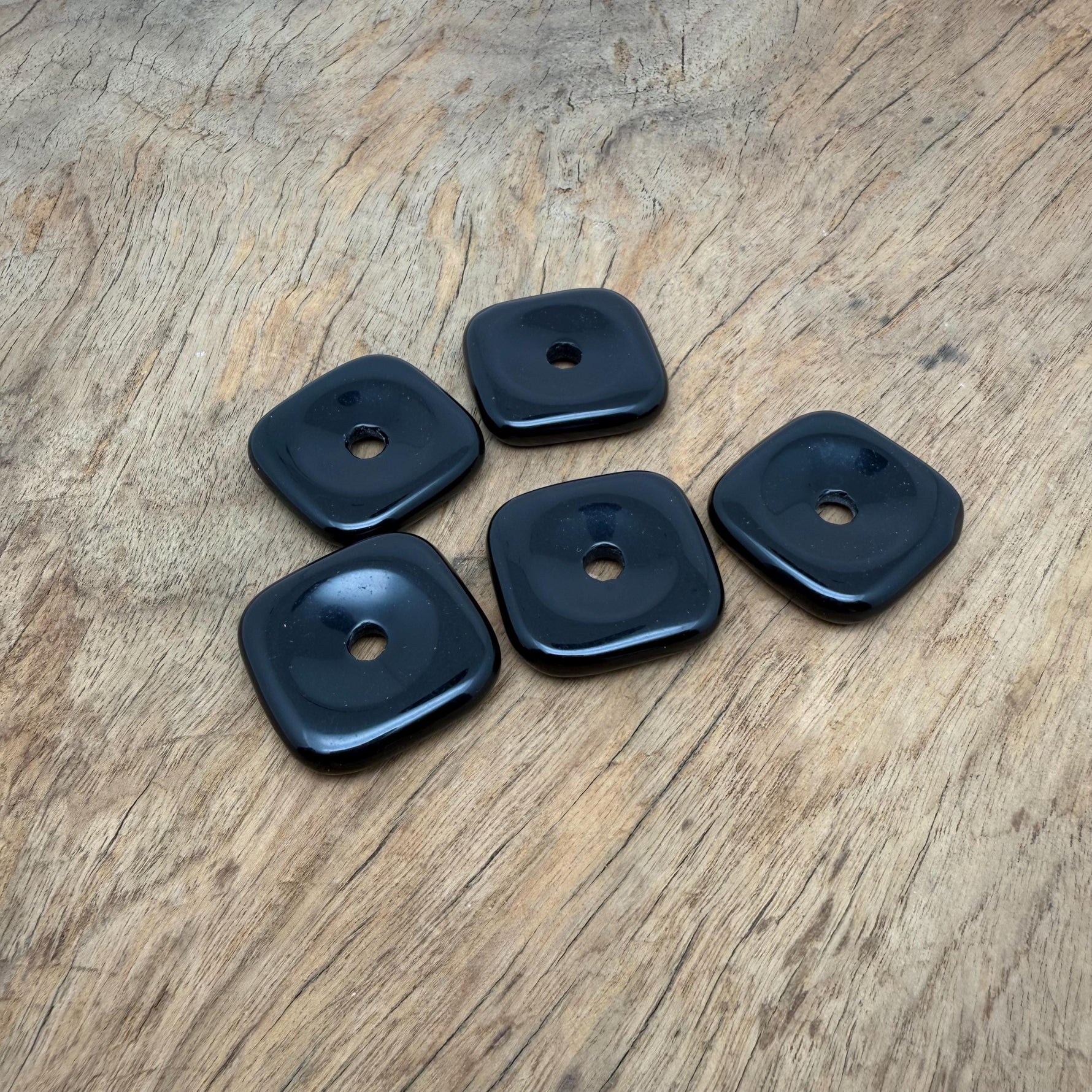 Obsidian square crystal donut from GemstoneGO with a 30mm Pi Stone design, showcasing a polished black gemstone shape.