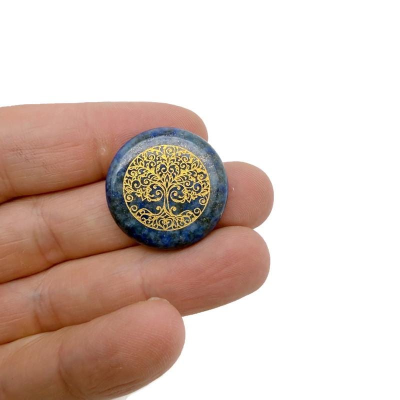 Crystal Tree of Life engraved gemstone amulet with drilled hole, symbolizing spiritual connection and natural beauty.