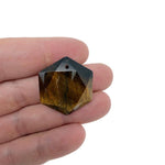 Faceted tiger eye hexagon crystal pendant on a necklace, showcasing the gemstone's warm brown and gold tones.