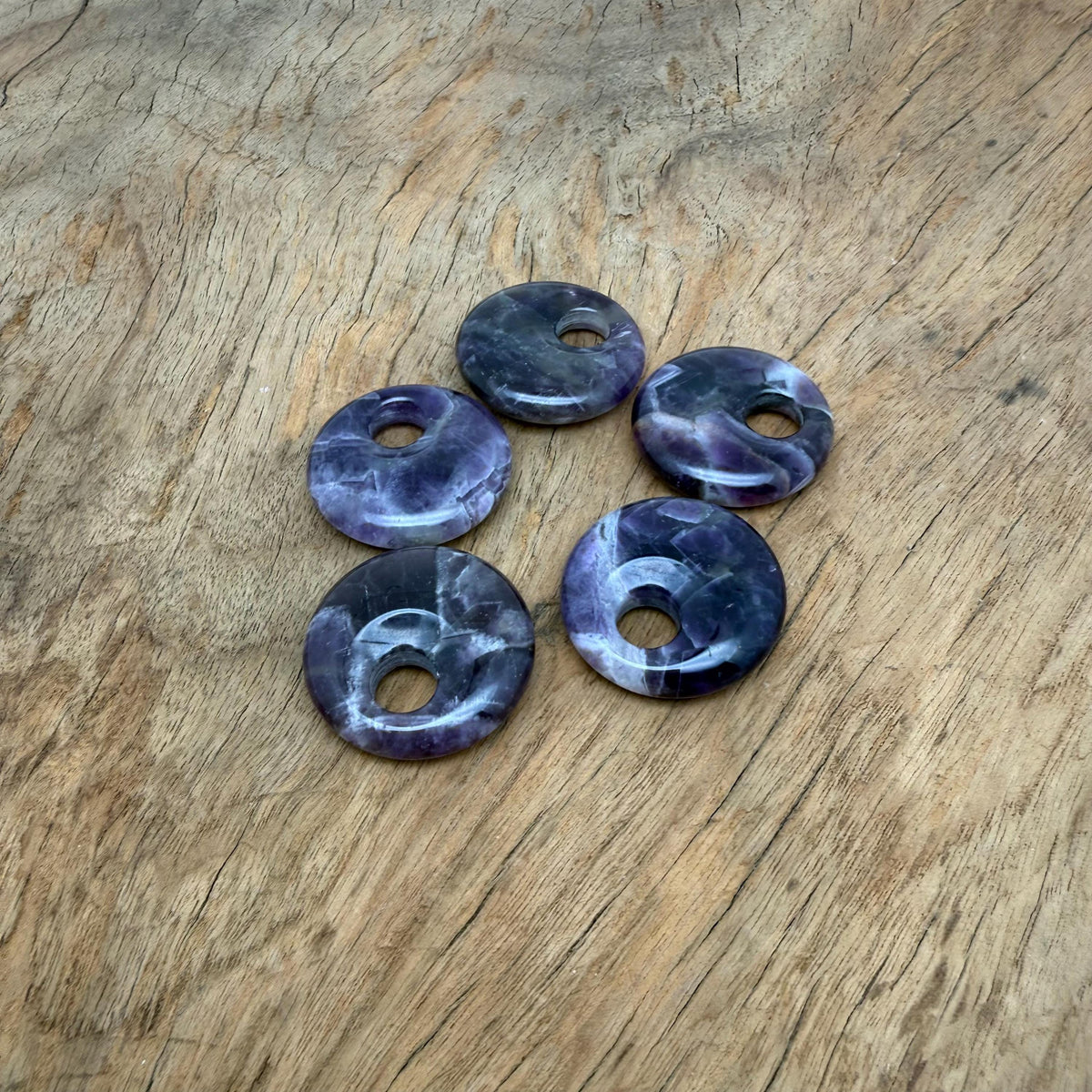 Amethyst crystal donut pendant, 30mm Pi stone from GemstoneGO, showing a polished purple gemstone with a hole in the center.