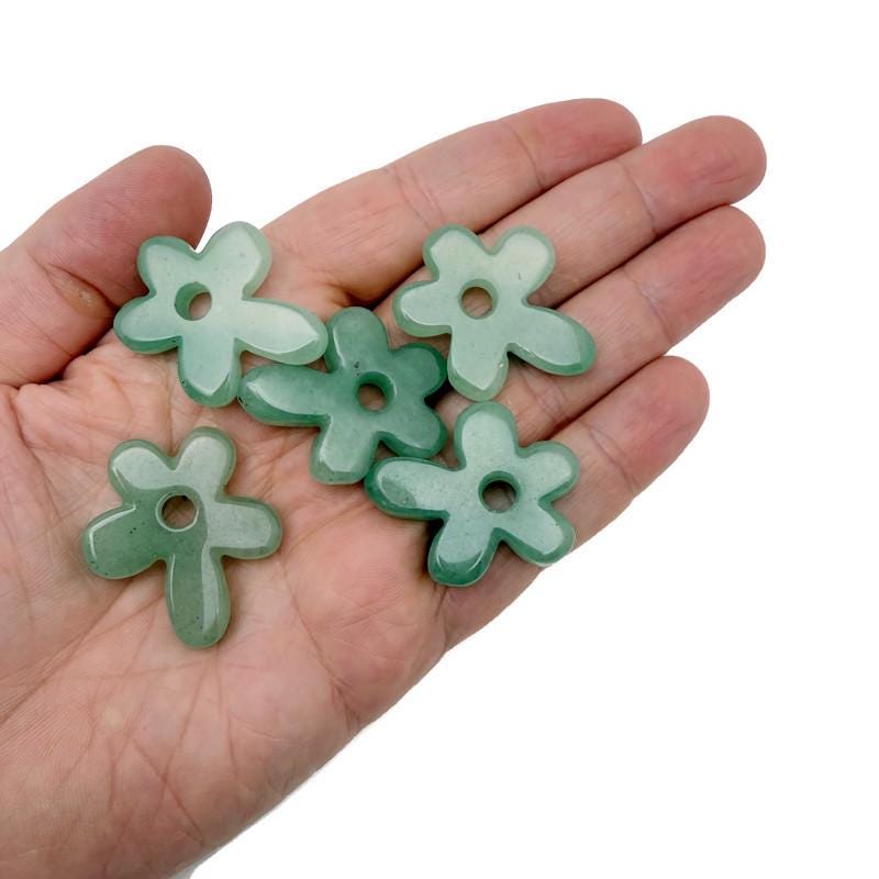 A carved aventurine gemstone pendant featuring a detailed crystal flower charm, showcasing vibrant green hues and intricate design.