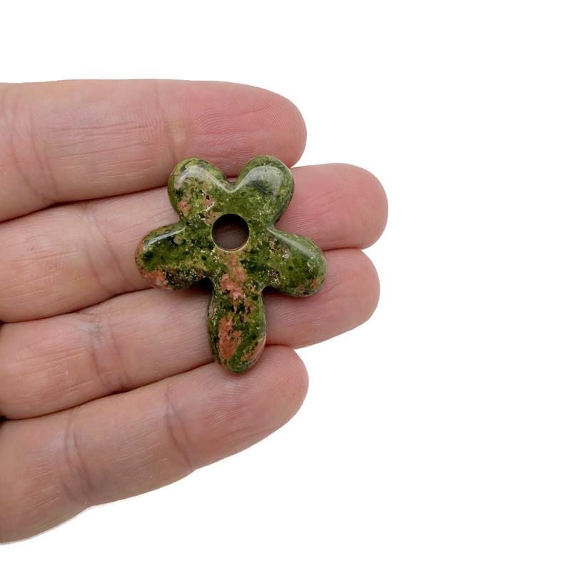 Unakite gemstone pendant featuring a carved crystal flower charm, showcasing vibrant pink and green hues with intricate details.
