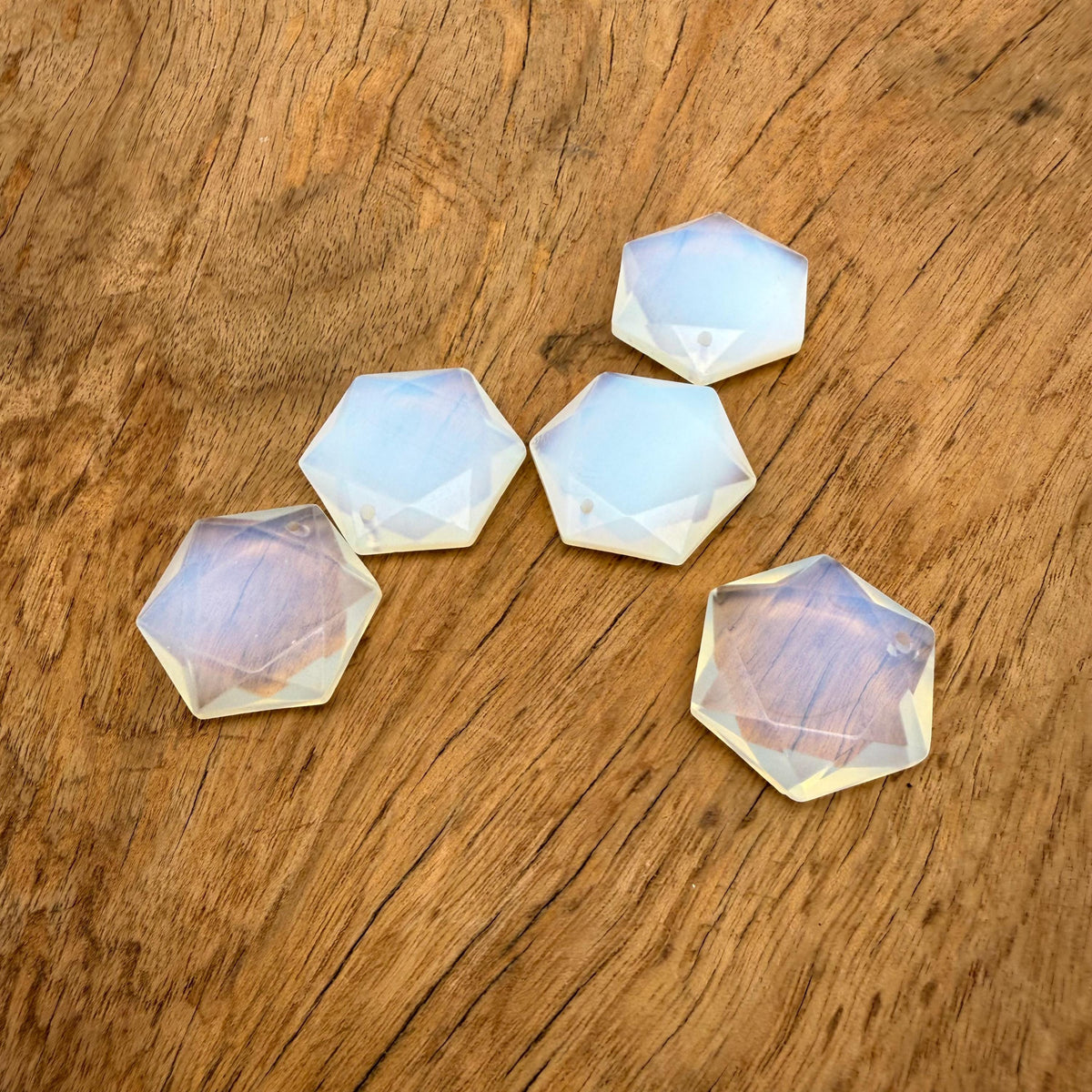 Faceted opalite hexagon crystal pendant necklace with a gemstone bead, showcasing a shimmering, translucent stone in a natural setting.