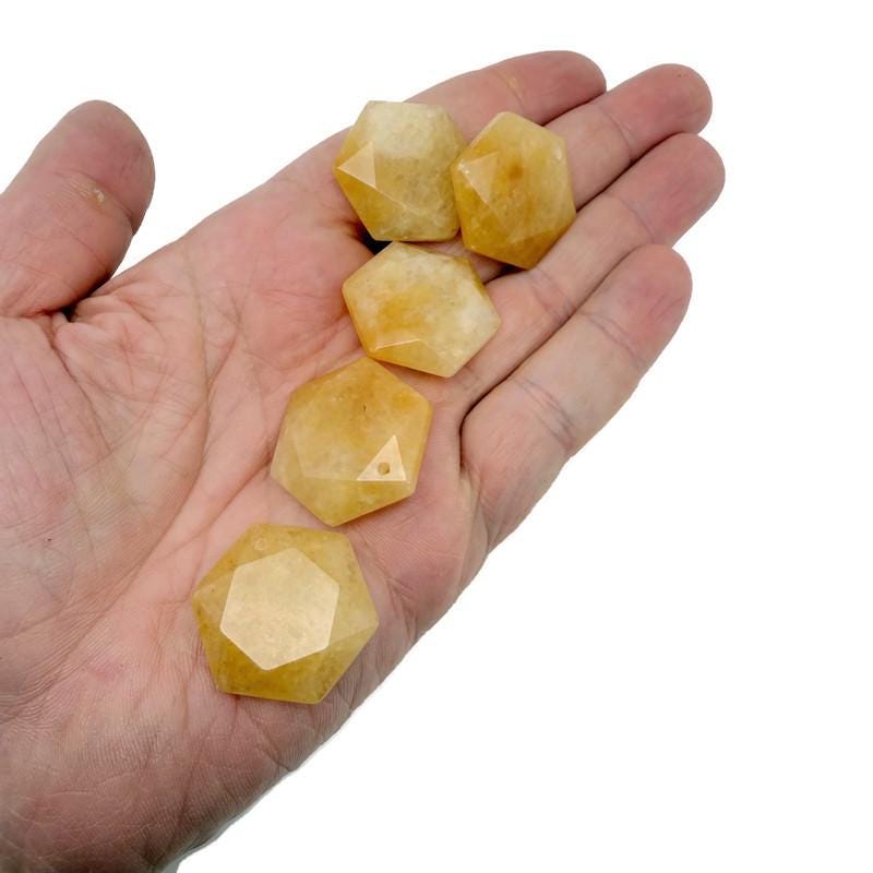 Yellow jade hexagon crystal pendant with faceted surface, attached to a beaded necklace, showcasing a vibrant gemstone jewelry piece.